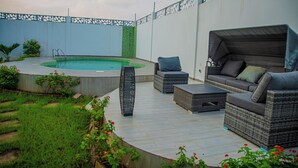 A backyard with a swimming pool, outdoor furniture, and a decorative fence. - La VILLA ASILI (Grand-Bassam)