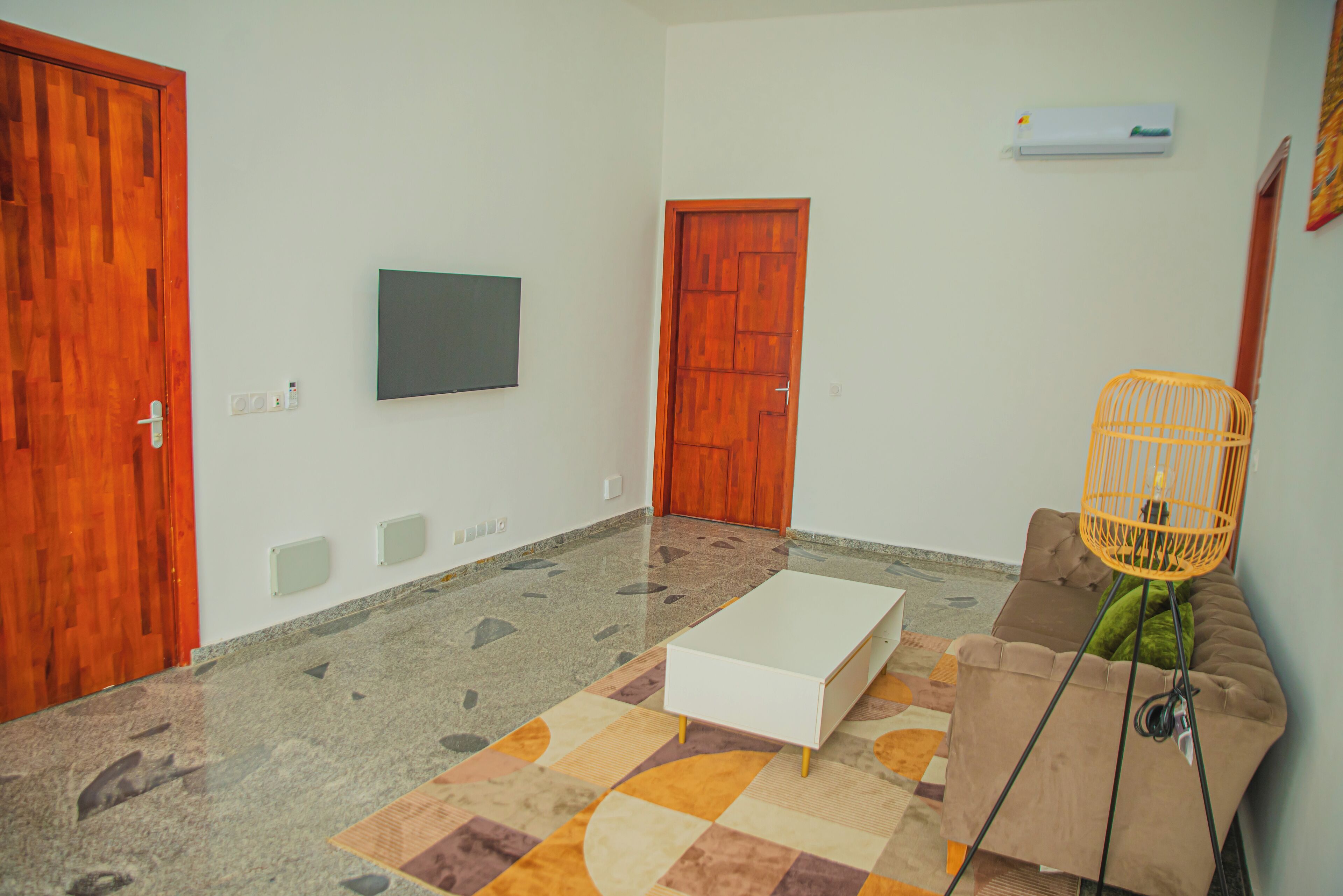 A room with a wooden door, a white sofa, a white coffee table, and a patterned rug.