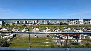 Ein Yachthafen mit modernen Gebäuden, Booten und freiem Blick auf das Meer.