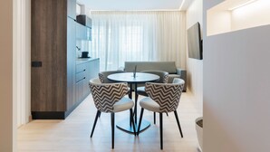 Un comedor moderno con una mesa redonda, dos sillas, un sofá y un televisor montado en la pared.