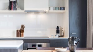 A modern kitchen with white cabinetry, a built-in oven, and a coffee machine.