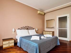 Una camera da letto con un letto, comodini, uno specchio e un condizionatore.