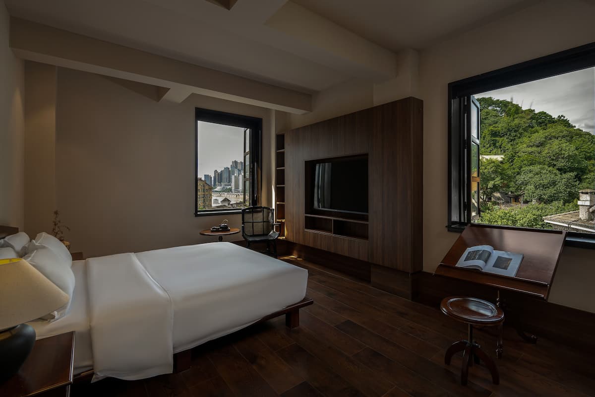 Ein Hotelzimmer mit Bett, Fernseher, kleinem Tisch und Fenster mit Stadtblick.