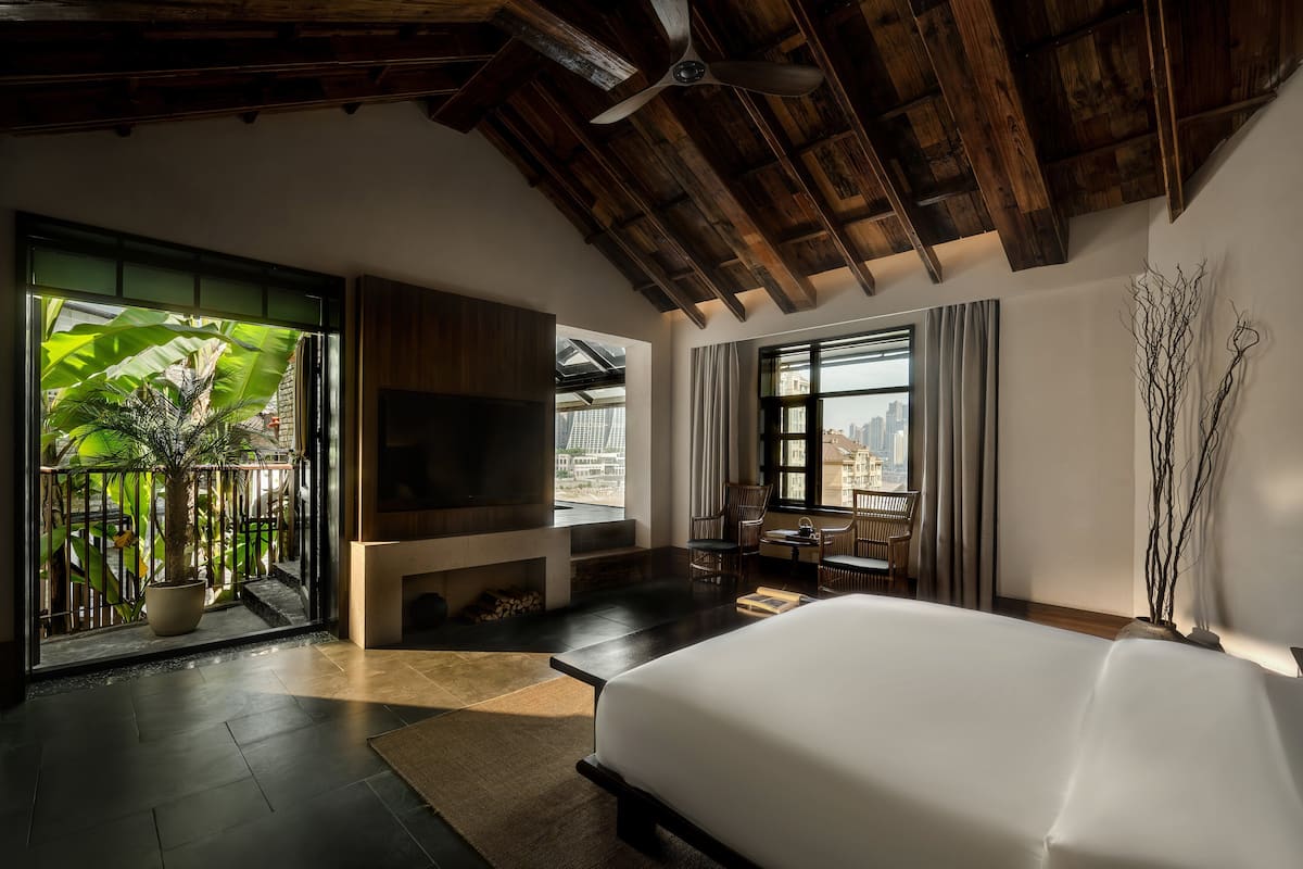 Ein geräumiges Schlafzimmer mit einem großen Bett, einem Fernseher und einem Balkon mit Blick auf die Stadt.