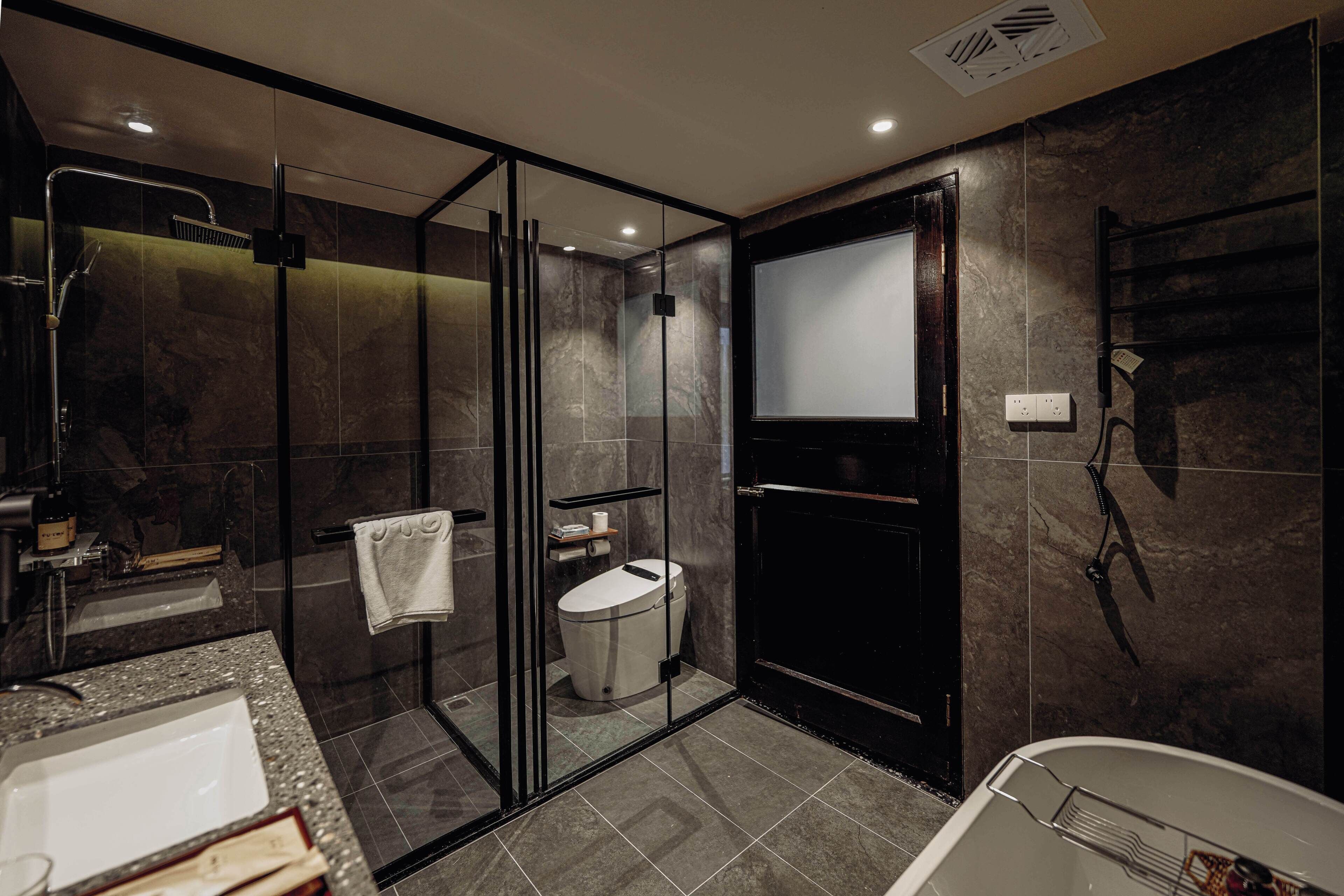 A modern bathroom with a glass-enclosed shower, a toilet, and a bathtub.