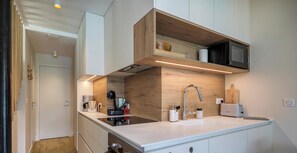 A modern kitchen with a built-in microwave, a sink, and a coffee machine.