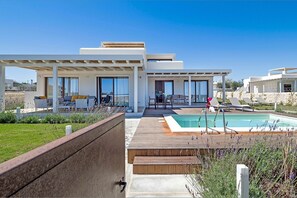 A modern house with a pool, outdoor seating, and a patio area.