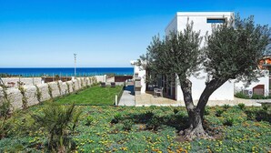 Un edificio moderno con un muro de piedra y un jardín lleno de flores amarillas.