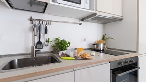A modern kitchen with stainless steel appliances, a built-in oven, and a variety of utensils and fresh produce on the counter. - Italianway Comfort - Watt 8 (Milan)