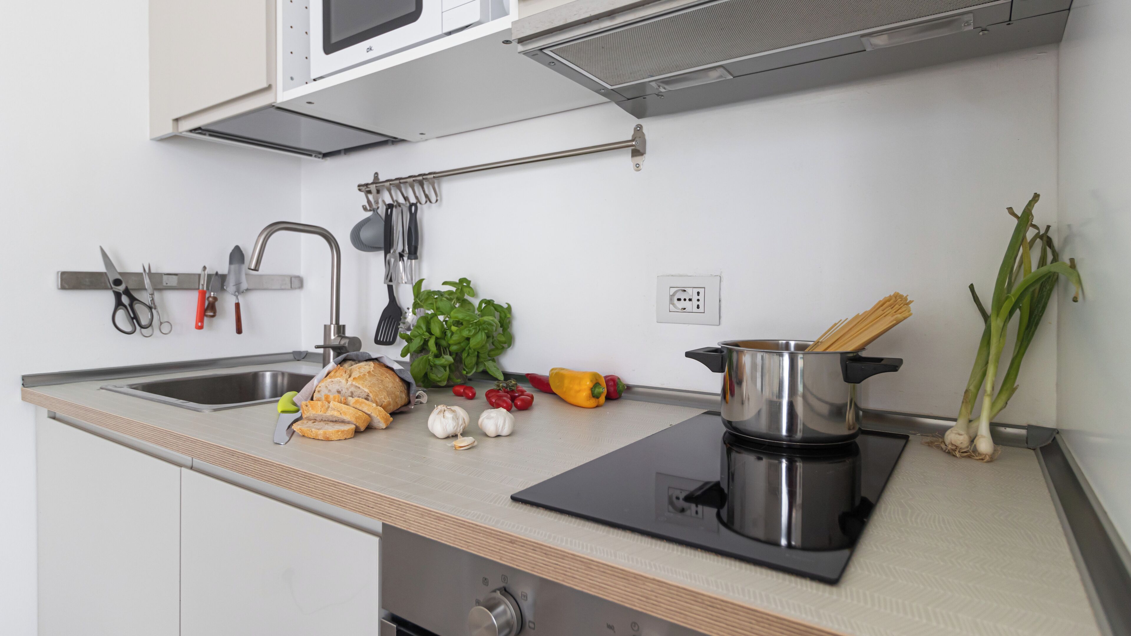 A kitchen with a sink, a stove, and various cooking utensils.