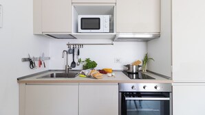 A modern kitchen with a built-in microwave, stainless steel appliances, and a variety of cooking utensils and fresh produce. - Italianway Comfort - Watt 8 (Milan)