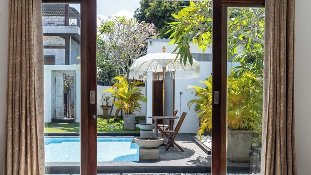 Une chambre avec vue sur une piscine, un espace salon extérieur et des plantes en pot.
