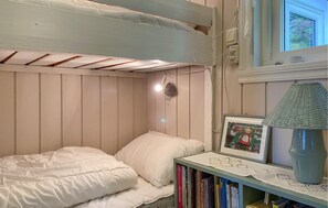 Una camera con un letto a castello, un comodino, una lampada e un quadro incorniciato.