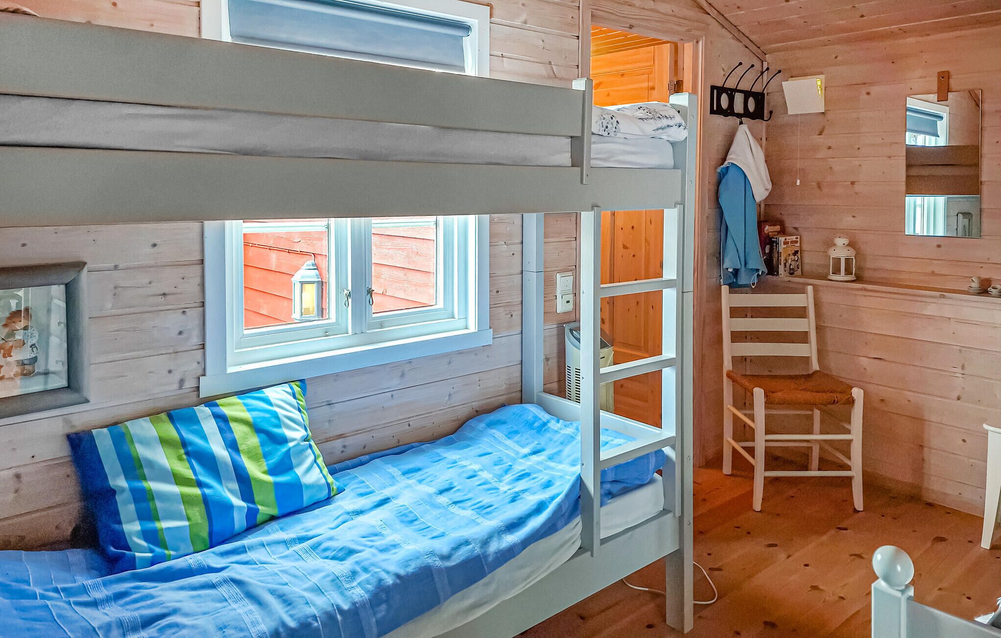 Dormitorio con literas, ventana, una silla y una mesita.