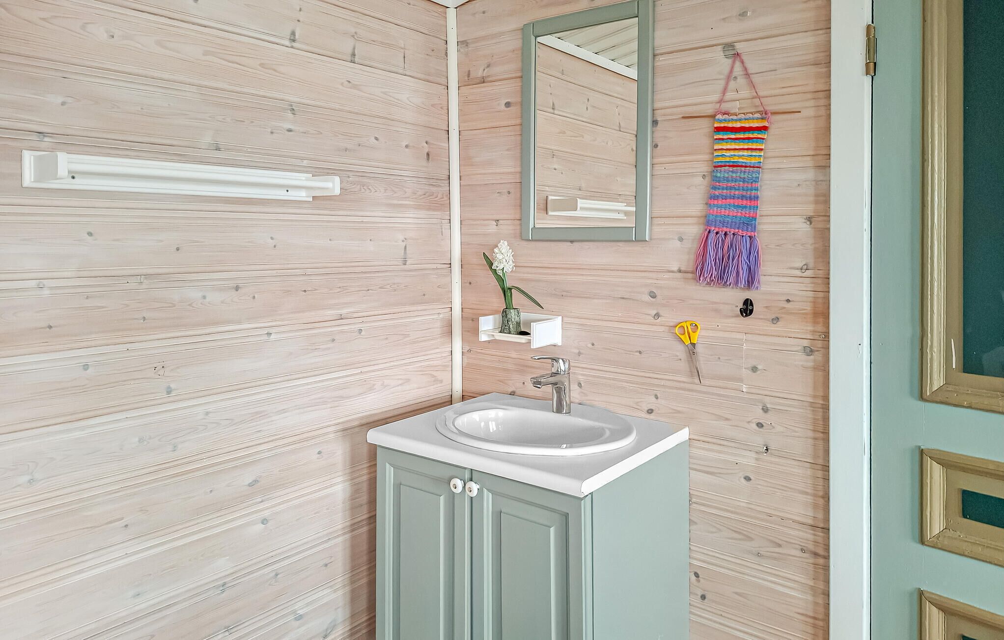 Un baño con pared de madera, un lavamanos blanco, un espejo y una toalla colgada.