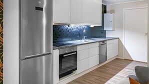 A modern kitchen with stainless steel appliances, white cabinetry, and a blue backsplash. - Amazing apartment in Bjorli with sauna (Bjorli)