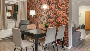 A dining area with a dark wooden table, six chairs, and a wall with a tropical leaf pattern. - Amazing apartment in Bjorli with sauna (Bjorli)