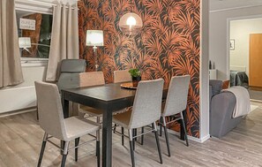 A dining area with a dark wooden table, six chairs, and a wall with a tropical leaf pattern.