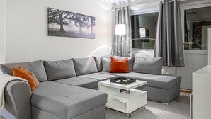 A modern living room with a grey sectional sofa, a white coffee table, and a painting of trees on the wall. - Amazing apartment in Bjorli with sauna (Bjorli)