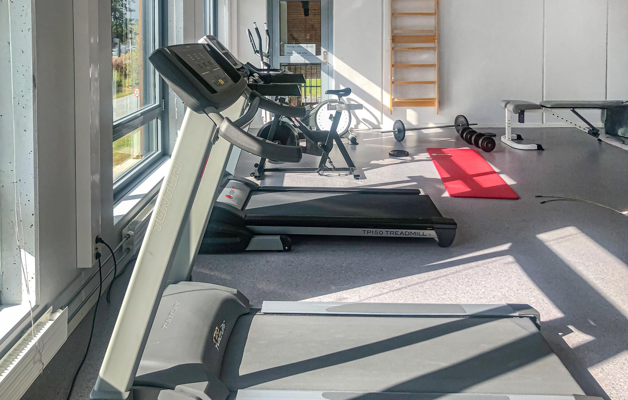 A gym with treadmills, a stationary bike, and a red mat.