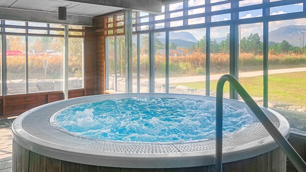 A hot tub with a view of mountains and a wooden deck. - Amazing apartment in Bjorli with sauna (Bjorli)
