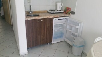 Uma cozinha compacta com pia, cafeteira e geladeira com compartimento para congelados.