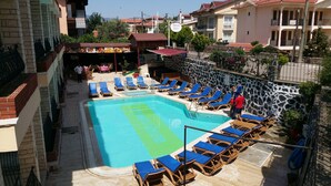 A swimming pool with blue lounge chairs and a stone wall. - Özlem  1 Apart (Marmaris)