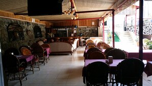 A restaurant with a stone wall, wooden ceiling, and a bar area. - Özlem  1 Apart (Marmaris)