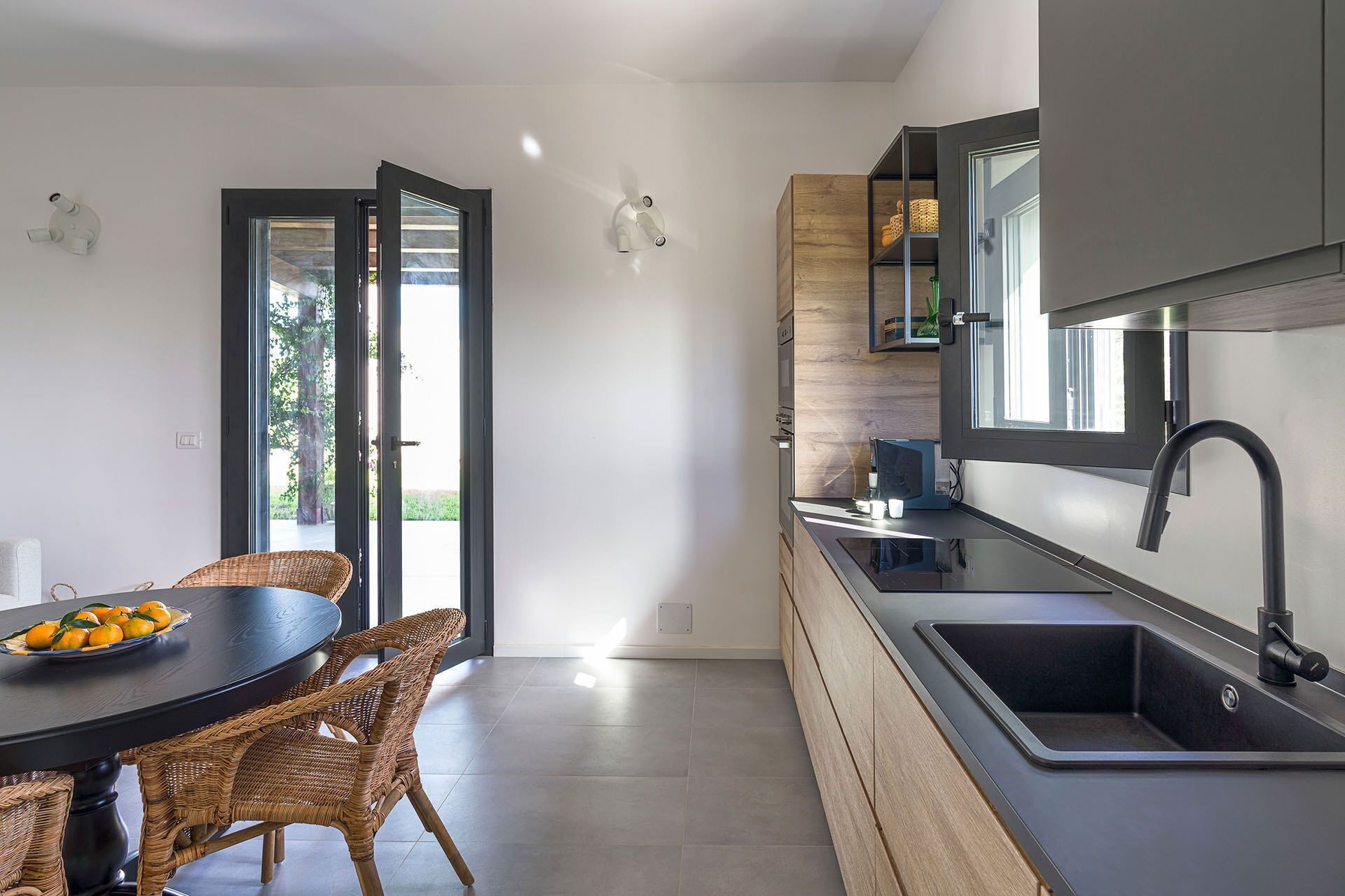 A modern kitchen with a dark countertop, a built-in oven, and a large window.