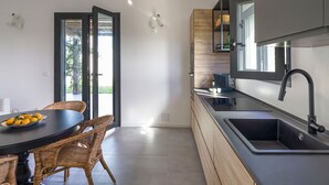 Eine moderne Küche mit dunkler Arbeitsplatte, einem Einbauofen und einem großen Fenster.