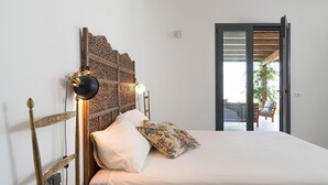 Ein Schlafzimmer mit einem hölzernen Kopfteil, einem Bett mit einem blumigen Kissen und einem Nachttisch mit einer Lampe.