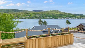 A wooden deck with a rope barrier, overlooking a lake with houses in the background. - 5 bedroom awesome home in Eidsvåg i Romsdal (Eidsvåg i Romsdal)