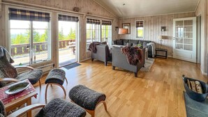 Un vaste espace de vie doté d’un plancher en bois, d’un ensemble de canapés et d’une table à manger agrémentée d’un saladier.