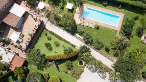 Vista aerea di una proprietà con piscina, prati curati e diverse piante e arbusti.
