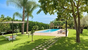 Un giardino sul retro con piscina, un pergolato e un piccolo albero.