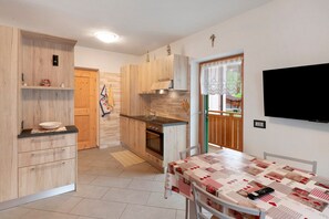 Una cucina con mobili in legno, forno integrato e tavolo da pranzo con tovaglia trapuntata.