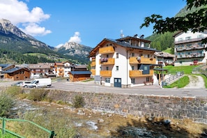 Un village de montagne aux maisons traditionnelles en bois, doté d’un pont de pierre et offrant une vue dégagée sur les montagnes.