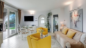 A modern living room with a sofa, yellow armchair, and dining area. - Il Silenzio House- Manerba del Garda Villa With Garden (Manerba del Garda)