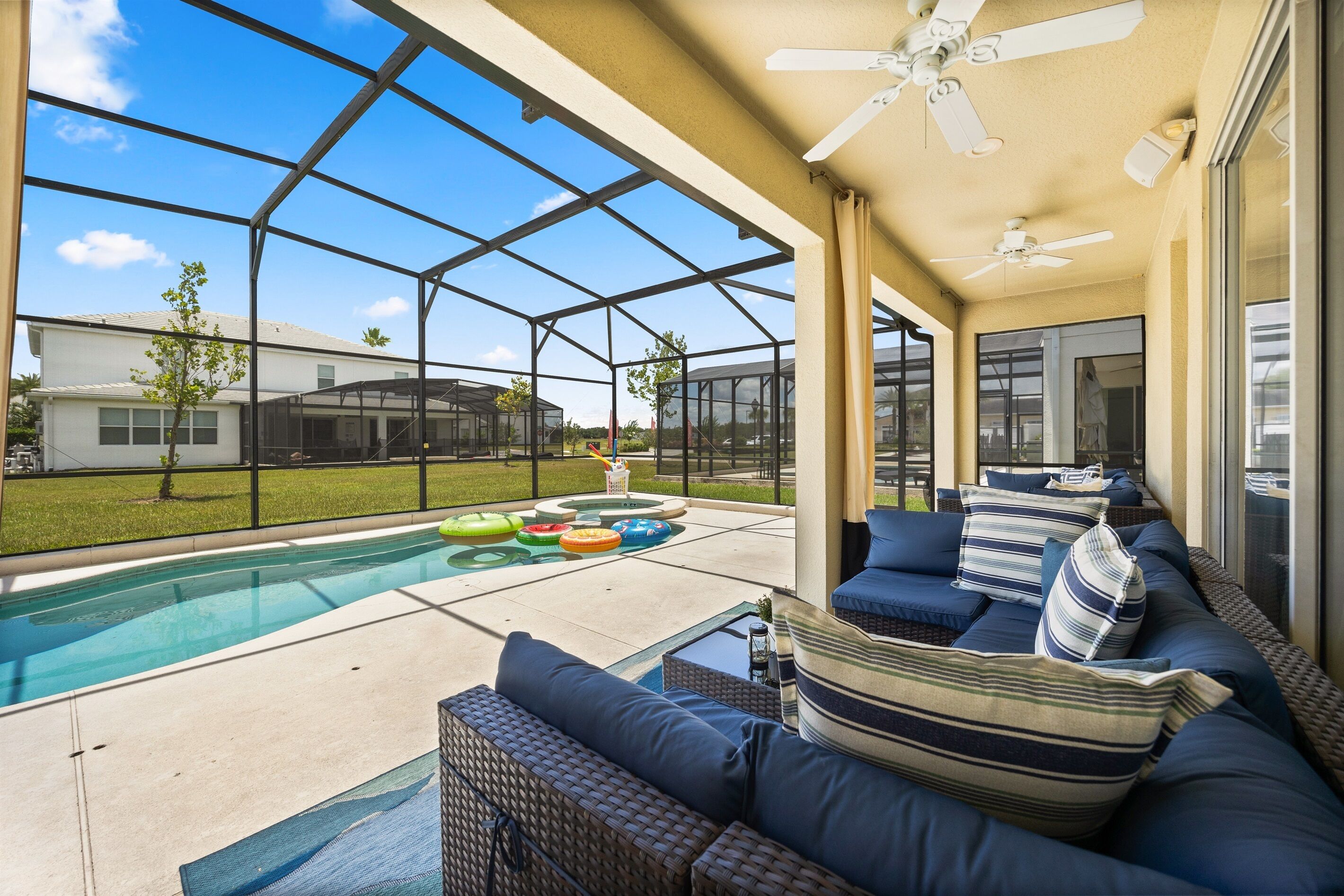 Un patio couvert avec une piscine, du mobilier d’extérieur et une vue sur une maison.