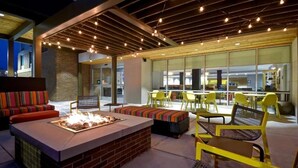 An outdoor seating area with a fire pit, yellow chairs, and a brick fireplace. - Spacious Room Near Entrust Bank Arena – Ideal for Sports Enthusiasts (Wichita)