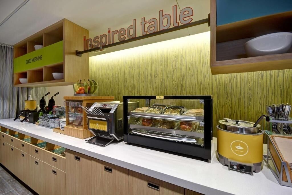 A breakfast area with a self-service station, a display case with pastries, and a coffee machine.