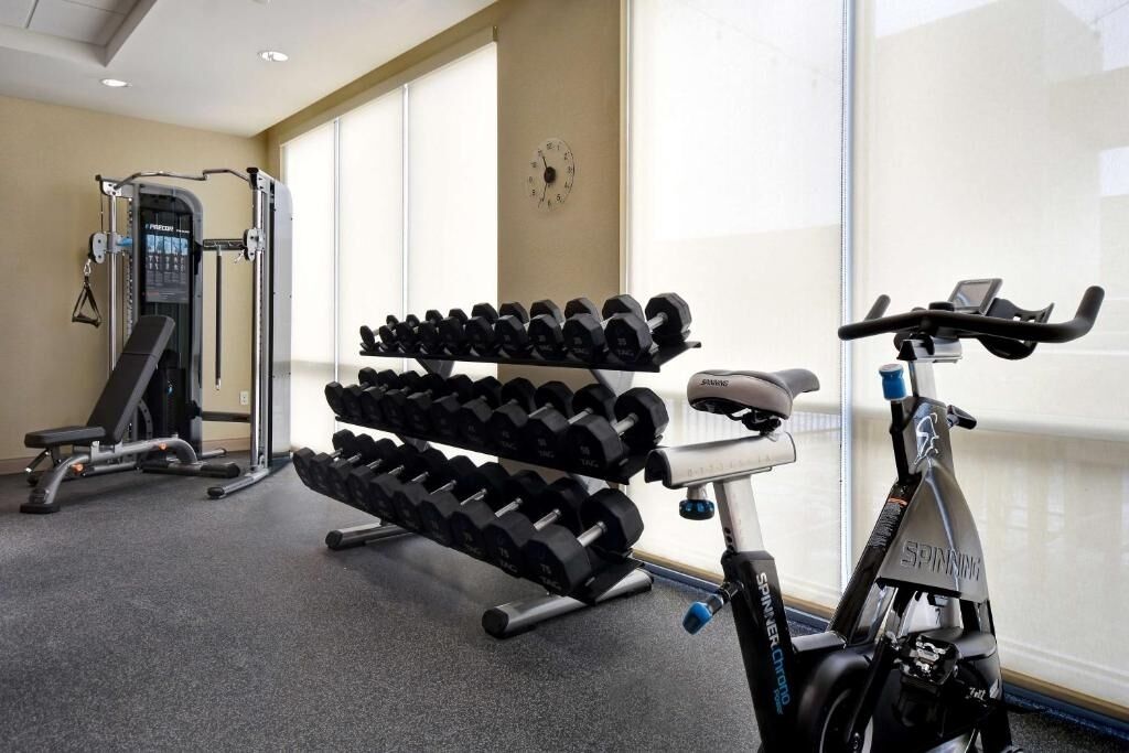 A gym with weightlifting equipment, dumbbells, and an exercise bike.