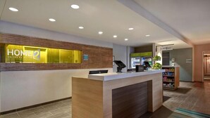A hotel reception area with a reception desk, a digital kiosk, and a small kitchenette. - Roomy Suite for a Relaxing Stay – Close to Exciting Wichita Spots (Wichita)
