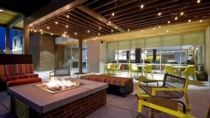 An outdoor seating area with a fire pit, yellow chairs, and a brick fireplace. - Comfortable Suite w/ Ample Breakfast Options Near Local Dining (Wichita)