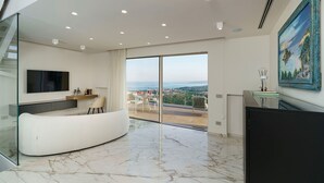 Een moderne woonkamer met een gebogen bank, een flatscreen televisie en een groot raam met uitzicht op de stad.