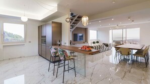 Een moderne keuken met een centraal eiland, een eethoek met een grote tafel en uitzicht op de stad.
