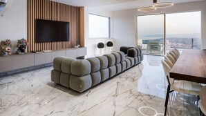 Een moderne woonkamer met een grote flatscreen televisie, een hoekbank, een eettafel en uitzicht op de stad.