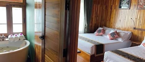 A wooden room with a bathtub, two beds, and a window.