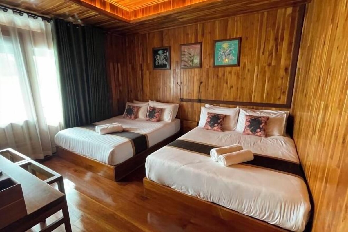 A room with two beds, wooden walls, and a wooden ceiling.