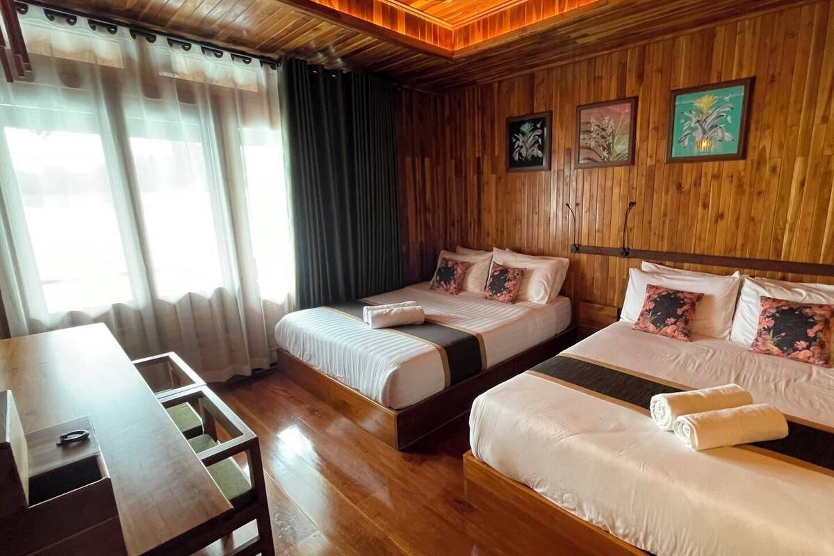 A hotel room with two beds, wooden paneling, and artwork on the walls.